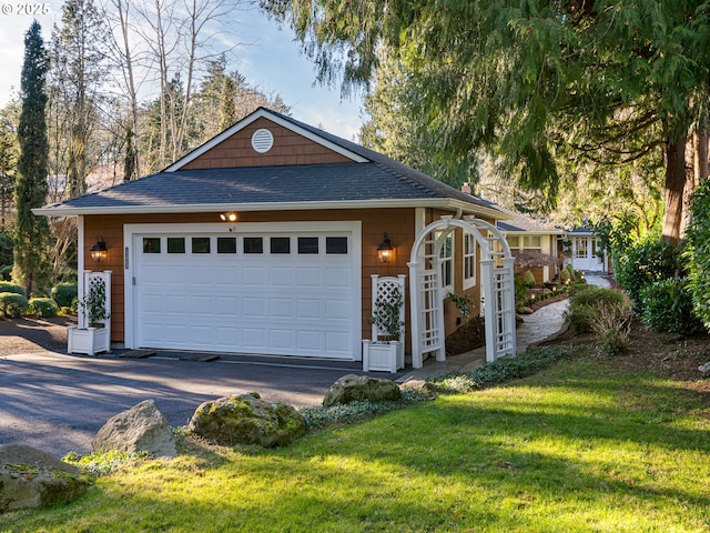 view of front of property featuring a shingled roof, a front yard, and a detached garage