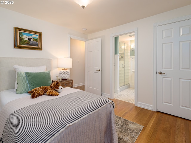 bedroom featuring baseboards, ensuite bath, and light wood finished floors