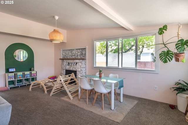 carpeted dining space featuring beamed ceiling and a fireplace