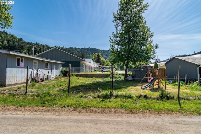 view of yard featuring central air condition unit, a playground, and fence