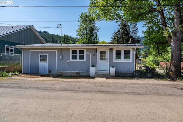 view of front facade with fence, metal roof, and crawl space