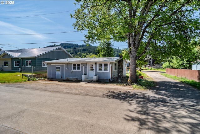 ranch-style home featuring fence, metal roof, and driveway