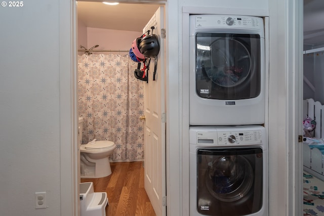 laundry room with laundry area, stacked washer / dryer, and wood finished floors