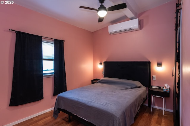 bedroom with a ceiling fan, baseboards, a wall unit AC, and wood finished floors