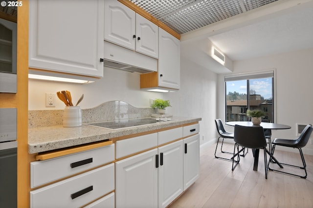 kitchen with white cabinets, black electric stovetop, and light wood-type flooring