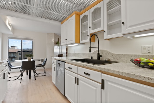 kitchen featuring sink, white cabinetry, dishwasher, light wood-type flooring, and light stone countertops