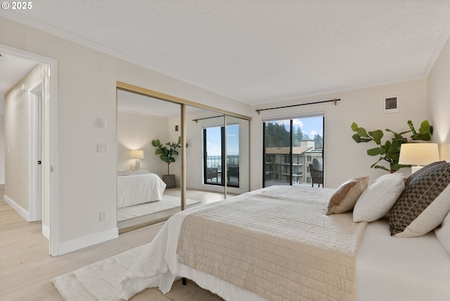 bedroom featuring a closet, crown molding, access to exterior, a textured ceiling, and light hardwood / wood-style flooring