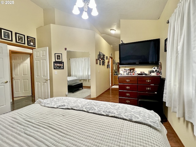 bedroom featuring vaulted ceiling, wood-type flooring, an inviting chandelier, and a closet