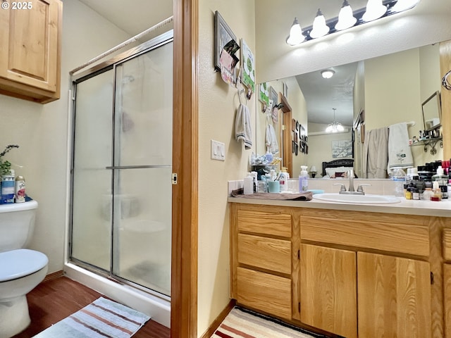 bathroom featuring toilet, wood-type flooring, vanity, and a shower with shower door