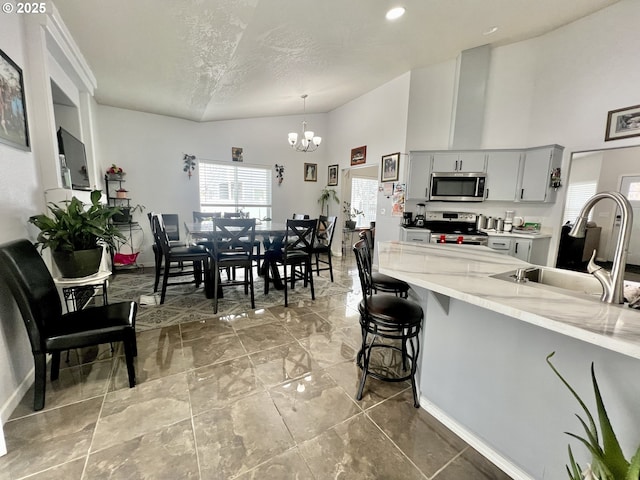 kitchen with sink, a kitchen bar, hanging light fixtures, a notable chandelier, and stainless steel appliances