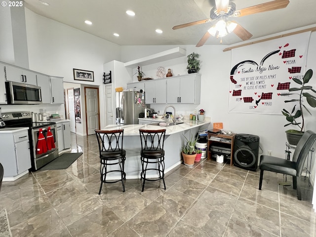 kitchen featuring appliances with stainless steel finishes, a breakfast bar, white cabinets, ceiling fan, and kitchen peninsula