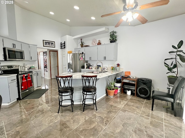 kitchen featuring appliances with stainless steel finishes, sink, a kitchen breakfast bar, kitchen peninsula, and white cabinets