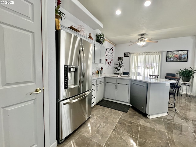 kitchen featuring sink, a kitchen breakfast bar, ceiling fan, kitchen peninsula, and stainless steel appliances