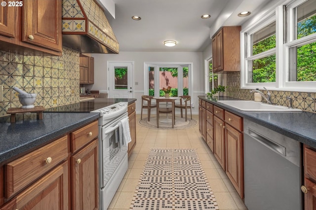 kitchen with decorative backsplash, white range with electric cooktop, dishwasher, a sink, and premium range hood