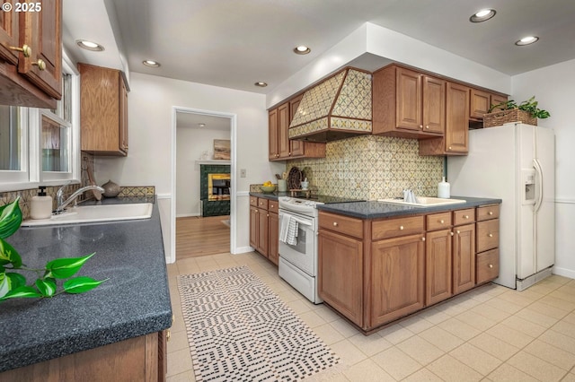 kitchen with light tile patterned floors, backsplash, white appliances, and a sink