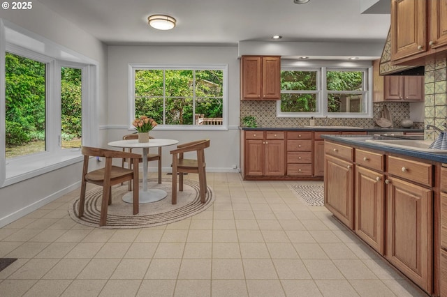 kitchen featuring brown cabinets, dark countertops, decorative backsplash, and baseboards