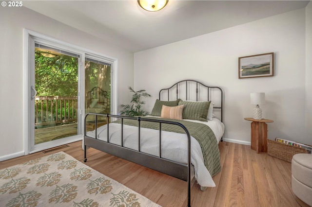 bedroom with baseboards, visible vents, wood finished floors, and access to exterior