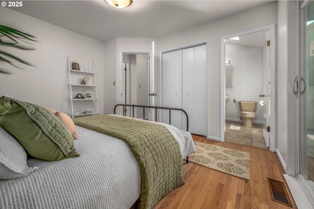 bedroom with a closet, light wood-type flooring, ensuite bath, and visible vents