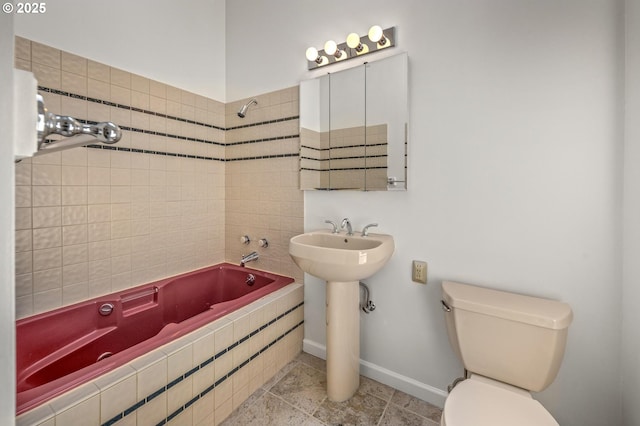 full bath featuring a sink, tile patterned flooring, toilet, tiled shower / bath, and baseboards