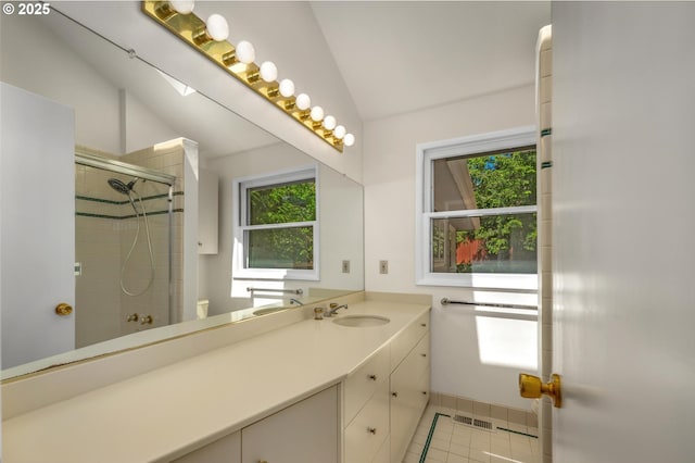 bathroom with a tile shower, vanity, tile patterned floors, lofted ceiling, and visible vents