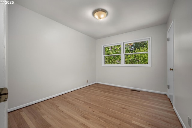 empty room with baseboards, light wood-type flooring, and visible vents