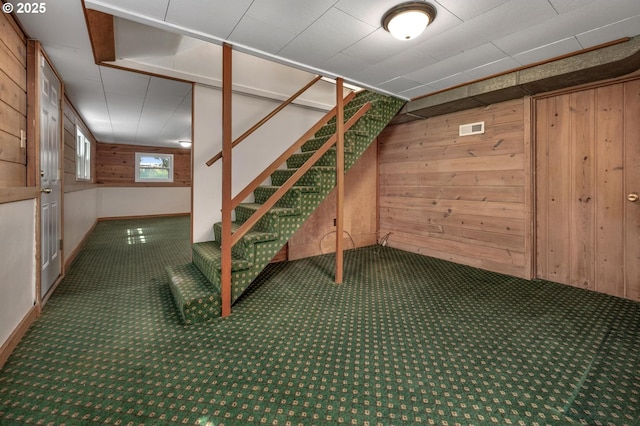basement with visible vents, stairway, wood walls, and carpet