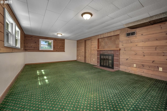 unfurnished living room with visible vents, baseboards, carpet floors, and wooden walls