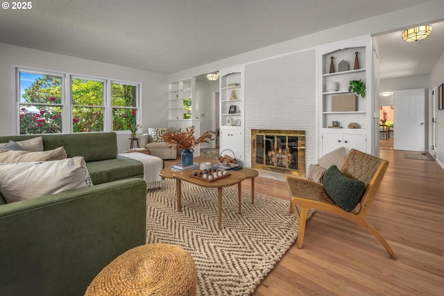 living area featuring built in shelves, wood finished floors, and a fireplace