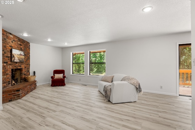 93933 Marcola Rd, Marcola, OR 97454 - living room featuring a textured ceiling, light wood-style floors, a fireplace, plenty of natural light, and recessed lighting