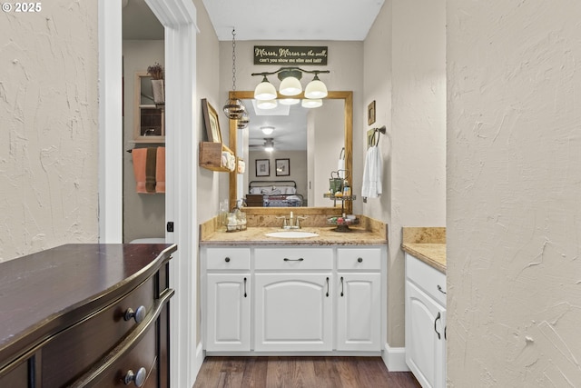 bathroom with a textured wall, wood finished floors, and vanity