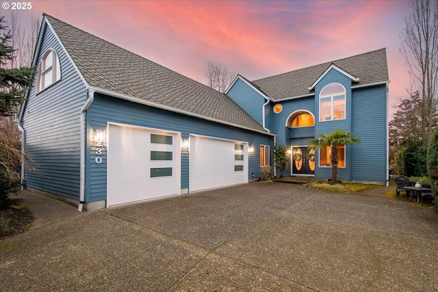 view of front of home featuring driveway, an attached garage, and roof with shingles