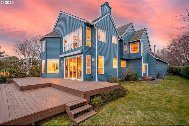 back of house at dusk with a lawn, a wooden deck, central AC, and a chimney