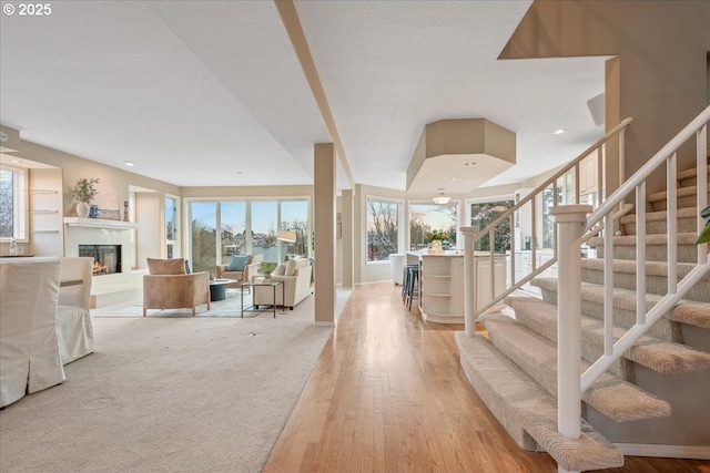 foyer entrance with a high end fireplace, recessed lighting, light wood-style flooring, and stairs