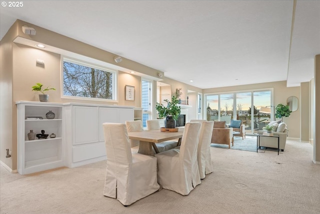 dining space with baseboards and light carpet