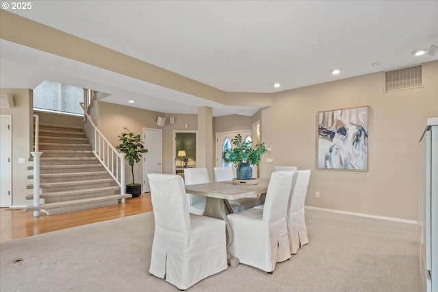 dining room with visible vents, baseboards, recessed lighting, stairs, and light colored carpet