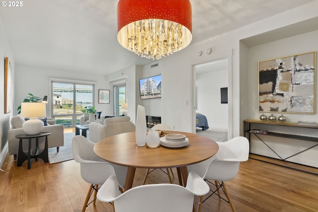 dining space featuring visible vents, wood finished floors, and a chandelier