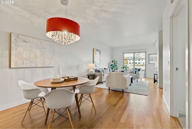 dining room featuring baseboards, light wood-style flooring, and a chandelier