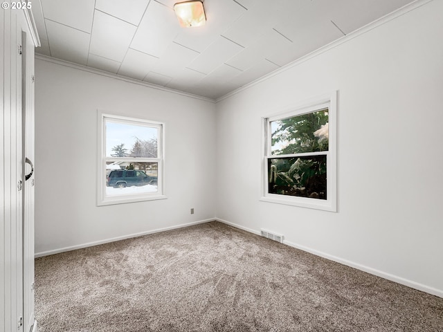 carpeted spare room featuring ornamental molding, visible vents, and baseboards