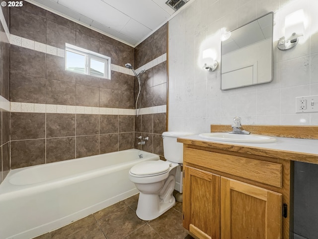 full bathroom with tile walls, visible vents, toilet, washtub / shower combination, and vanity