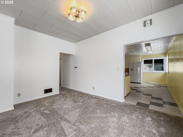 spare room featuring carpet flooring, visible vents, and baseboards