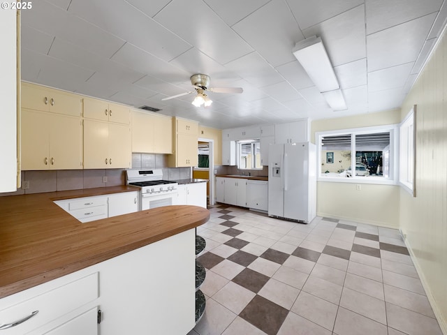 kitchen featuring white appliances, tasteful backsplash, visible vents, a ceiling fan, and cream cabinetry