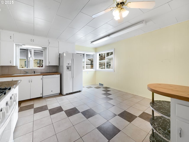 kitchen featuring white appliances, white cabinetry, plenty of natural light, and visible vents