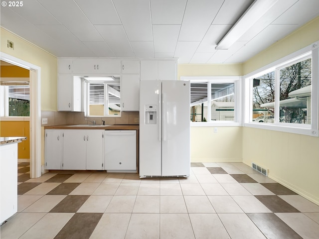 kitchen with dark countertops, visible vents, white cabinetry, a sink, and white appliances