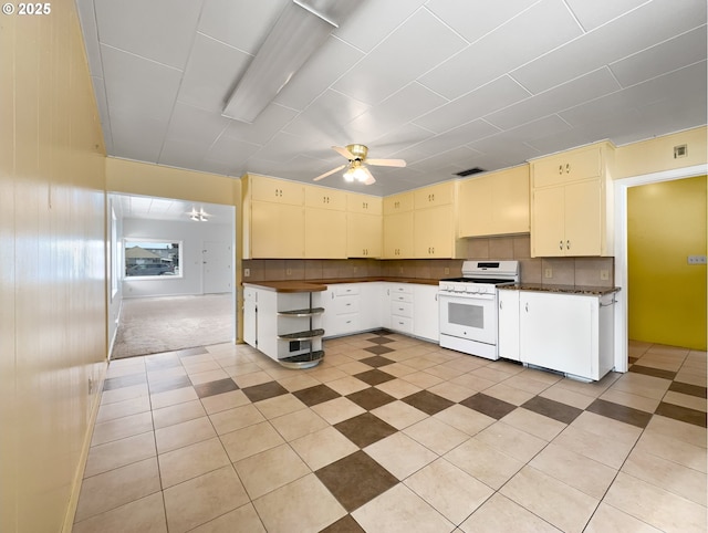 kitchen featuring dark countertops, tasteful backsplash, white range with gas stovetop, and cream cabinetry