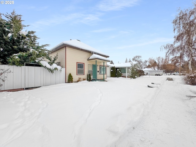 snow covered back of property with fence