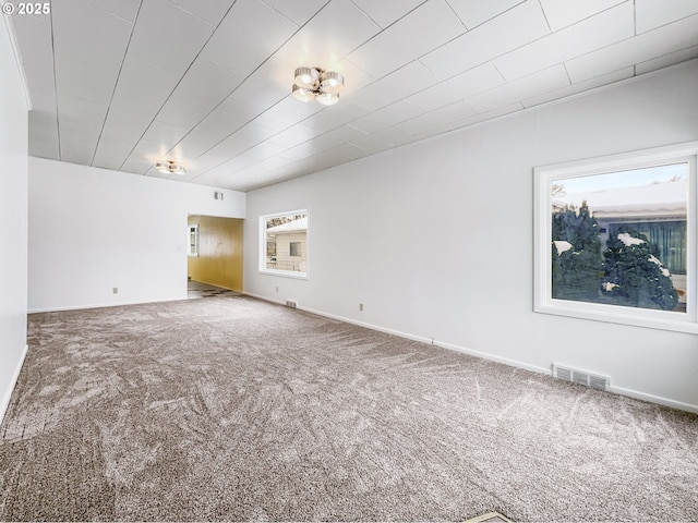 empty room featuring carpet, visible vents, and baseboards