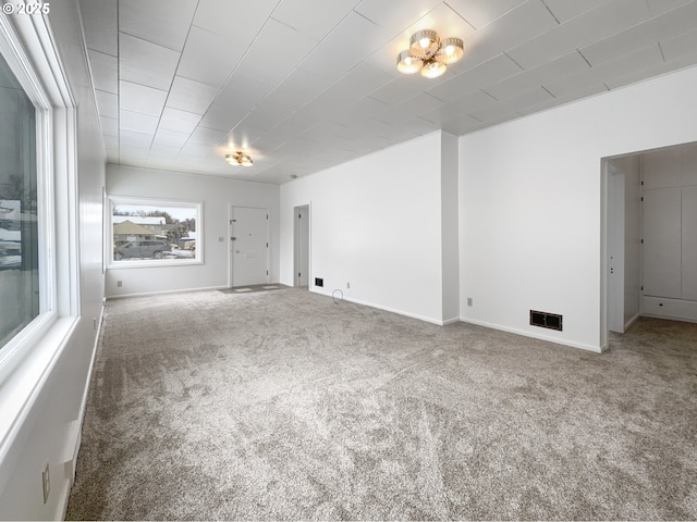 spare room featuring carpet floors, visible vents, and baseboards