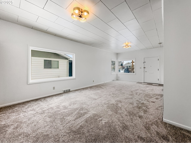 spare room with carpet, visible vents, and baseboards