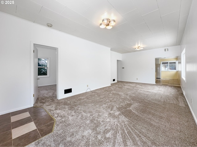 spare room featuring carpet and baseboards