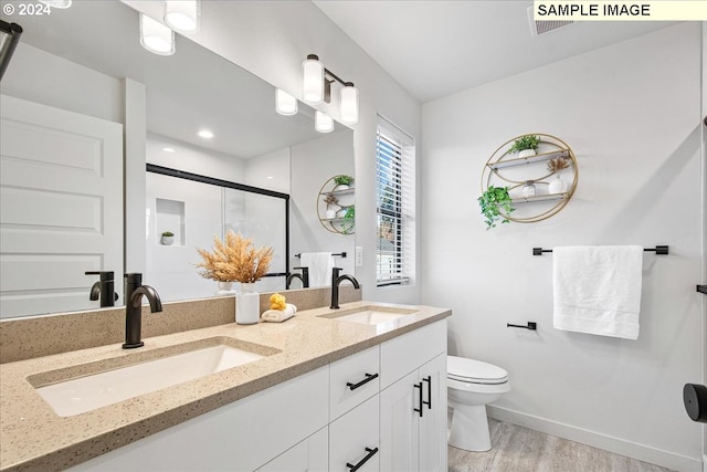 bathroom featuring vanity, toilet, wood-type flooring, and a shower with shower door